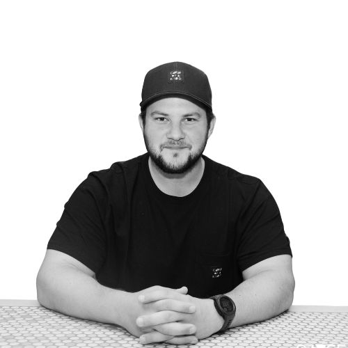 Studio headshot of Justin in a Cause of a Kind cap and black tee